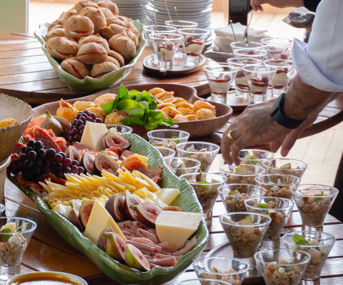 Mesa de coffee break com pães, queijos, frutas e porções individuais